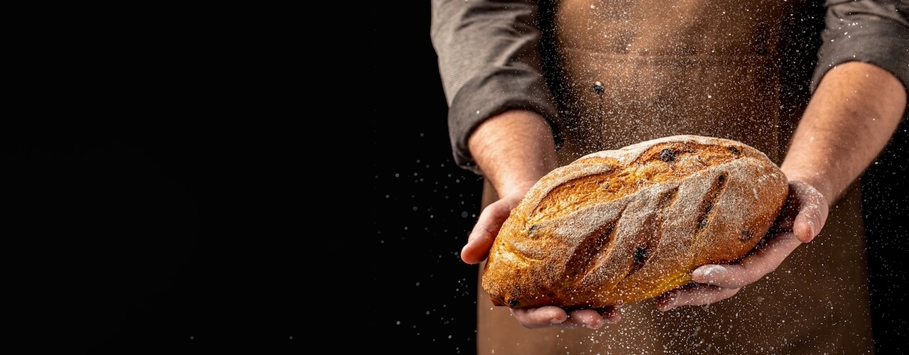 Man holding freshly bakes sourdough loaf